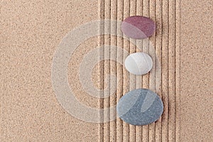 Three coloured pebbles on raked sand