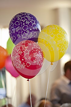 Three colourful 18th birthday party balloons, red and purple and yellow, at a party