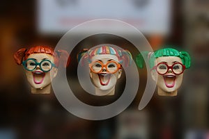 Three colourful fake laughing woman heads floating midair with different haircuts