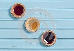 Three colourful jam tarts on a blue background