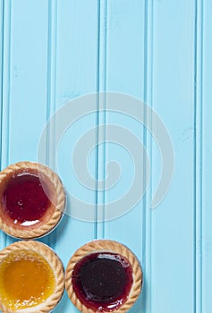 Three colourful jam tarts on a blue background