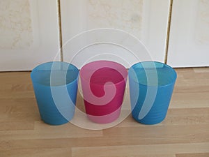 Three colourful plastic beakers on a wooden kitchen worktop