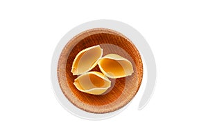 Three conchiglie rigate pasta or seashell macaroni in brown bowl isolated on white background.