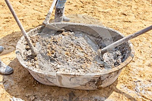 Three concrete workers mixing the cement and sand in salver, building construction site.