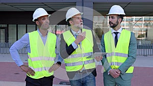 Three construction engineers having a discussion on building site.