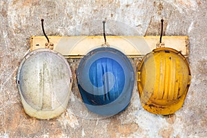 Three construction helmets hanging on a hat-rack