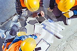 Three construction workers sitting on concrete and discussing