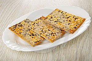 Three cookies with sunflower seeds, flaxseeds and sesame in plate on wooden table