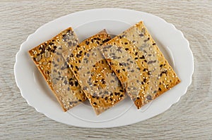 Three cookies with sunflower seeds, flaxseeds and sesame in plate on wooden table. Top view