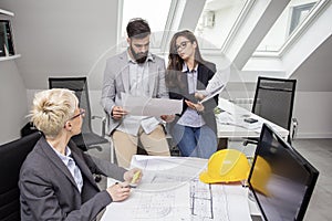 Three cooworkers with plans on table