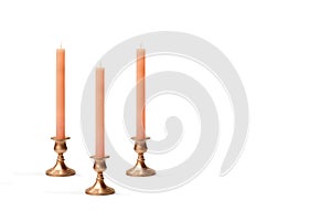 Three copper chandeliers with pink candles on a white background