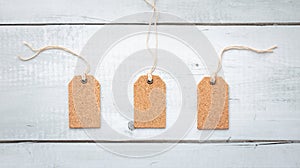 Three corkboard tags on white wood texture background