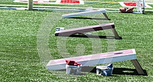 Three corn hole games set up on turf field