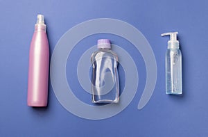 Three cosmetic bottles on blue colored paper bsckground