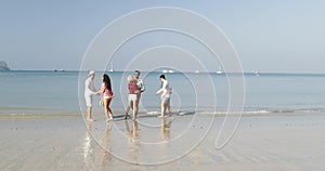 Three Couples Running On Beach To Water Holding Hands Happy Cheerful Men And Women Tourists On Vacation