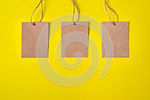 Three Craft brown paper tags isolated on yellow background. Sale price banner with copy space in minimal style