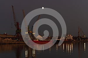 Three cranes in the port against clear evening sky.