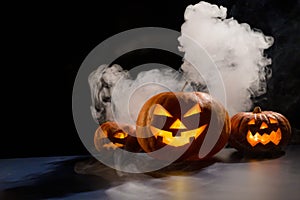 Three creepy halloween steaming pumpkins with a carved luminous smirk on a black background. A handmade jack-o-lantern