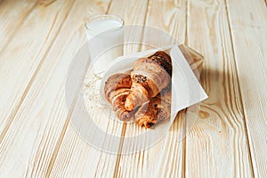 Three croissants with chocolate and milk on wood table