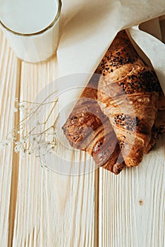 Three croissants with chocolate and milk on wood table