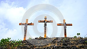 Three crosses of Jesus Christ on top of the hill with blue vibrant color sky with clouds background. Front view. Christianity.