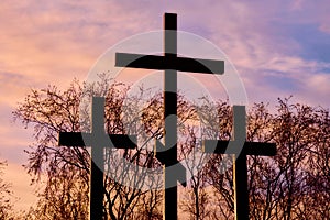 Three crosses in silhouette at sunset, dramatic sky