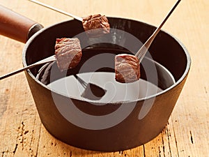 Three cubes of meat ready to dip in fondue