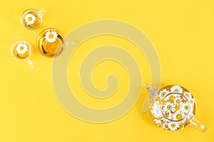 Three cup of tea and transparent teapot with camomile flowers on yellow background. Chamomile Tea Benefits Your Health concept.