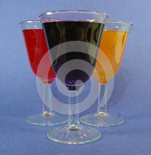 Three cups of cocktails mimosa, red wine and cabernet a blue background from a lateral view