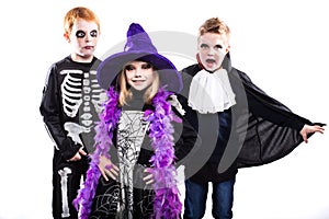 Three cute child dressed the Halloween costumes: witch, skeleton, vampire
