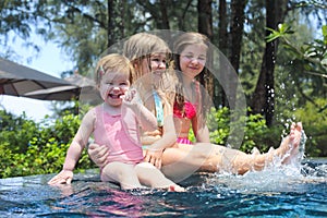 Three cute girls playing in swimming pool
