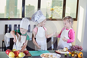 Three cute kids are preparing a fruit salad in kitchen