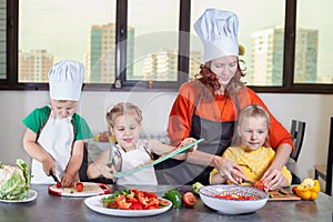 Three cute kids are preparing a salad in the kitchen