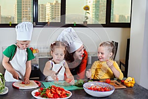 Three cute kids are preparing a salad in the kitchen