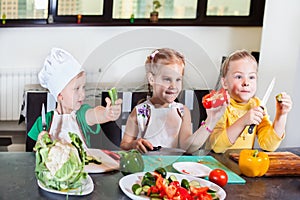 Three cute kids are preparing a salad in the kitchen