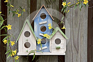 Three cute little birdhouses on wooden fence with flowers