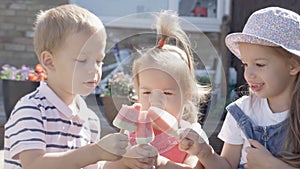 Three cute little Children enjoys delicious ice cream cone. Child eating watermelon popsicle. Kids Siblings snack sweets