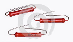 Three cylindrical carbon power resistors with bent lead wires on white background