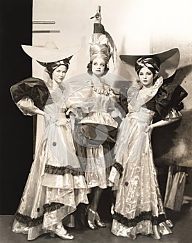Three dancers in long dresses and large hats