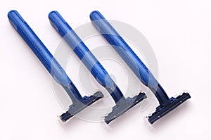 Three dark blue disposable plastic shavers
