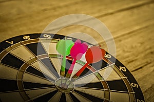 Three Dart arrow hitting in the target center of dartboard.