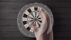 Three darts are aimed and thrown by hand and hit the dartboard on a black wooden background. Unlucky - none of the
