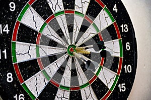 Three darts hit the center of the board while playing darts