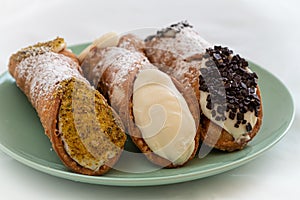 Three delicious cannoli on a green plate, typical Sicilian pastry