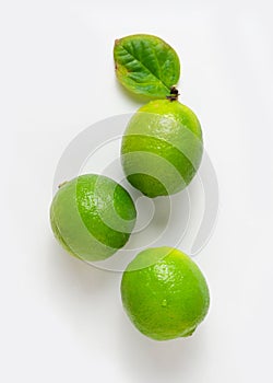 Three delicious limes with a leaf on a white background.