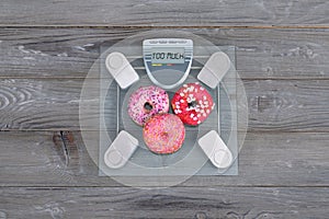 Three delicious pink donuts on a weight scale