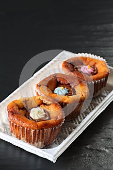 Three delicious small cheesecakes with melted chocolate and colorful sugar flowers icing in cupcake liners