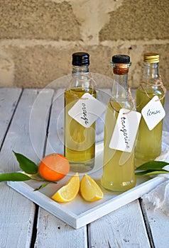 Three delicious yellow alcohol drinks in glass bottles and citrus fruit. Orange-flavored liqueur, Italian Limoncello liquor, tange
