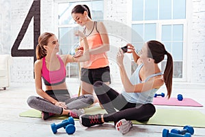 Three delighted women checking their training results in gym