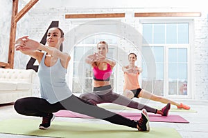 Three delighted women doing fitness exercises together